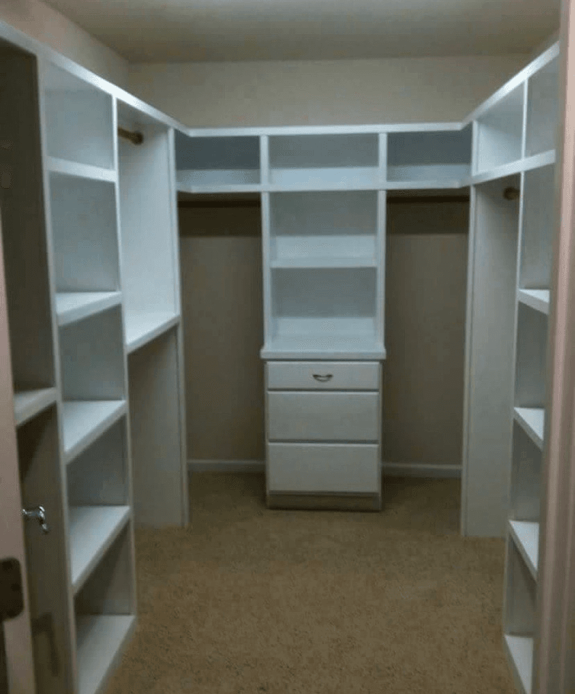 Walk-in closet with white built-in shelving and center dresser