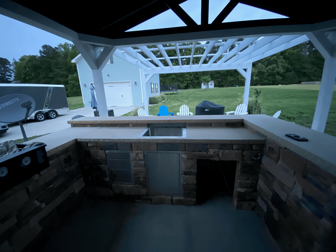 Stone outdoor kitchen bar under a timber pavilion at dusk