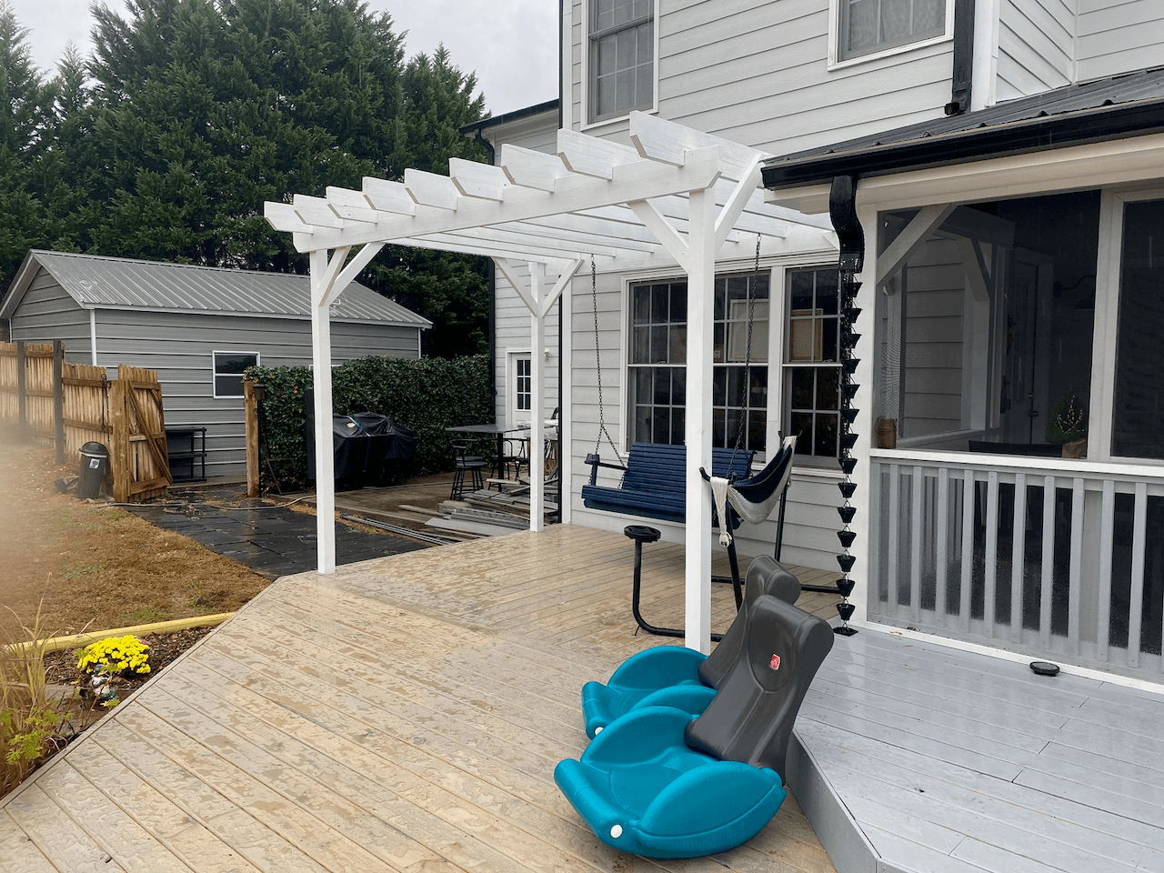 White pergola over a deck with a hanging porch swing
