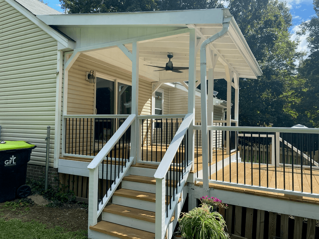 Covered porch with white posts, black balusters and new stairs