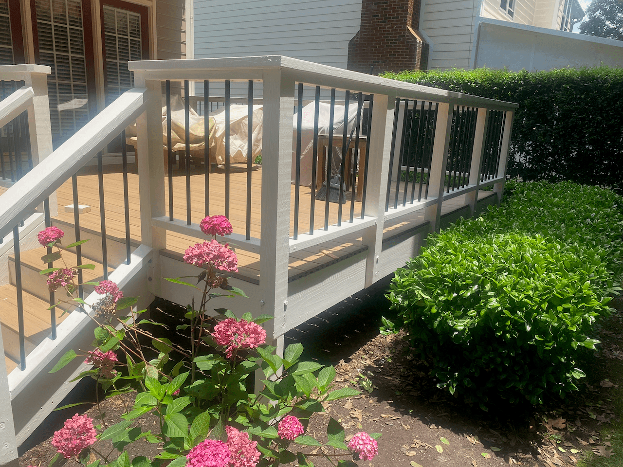 White deck railing with black balusters beside blooming hydrangeas